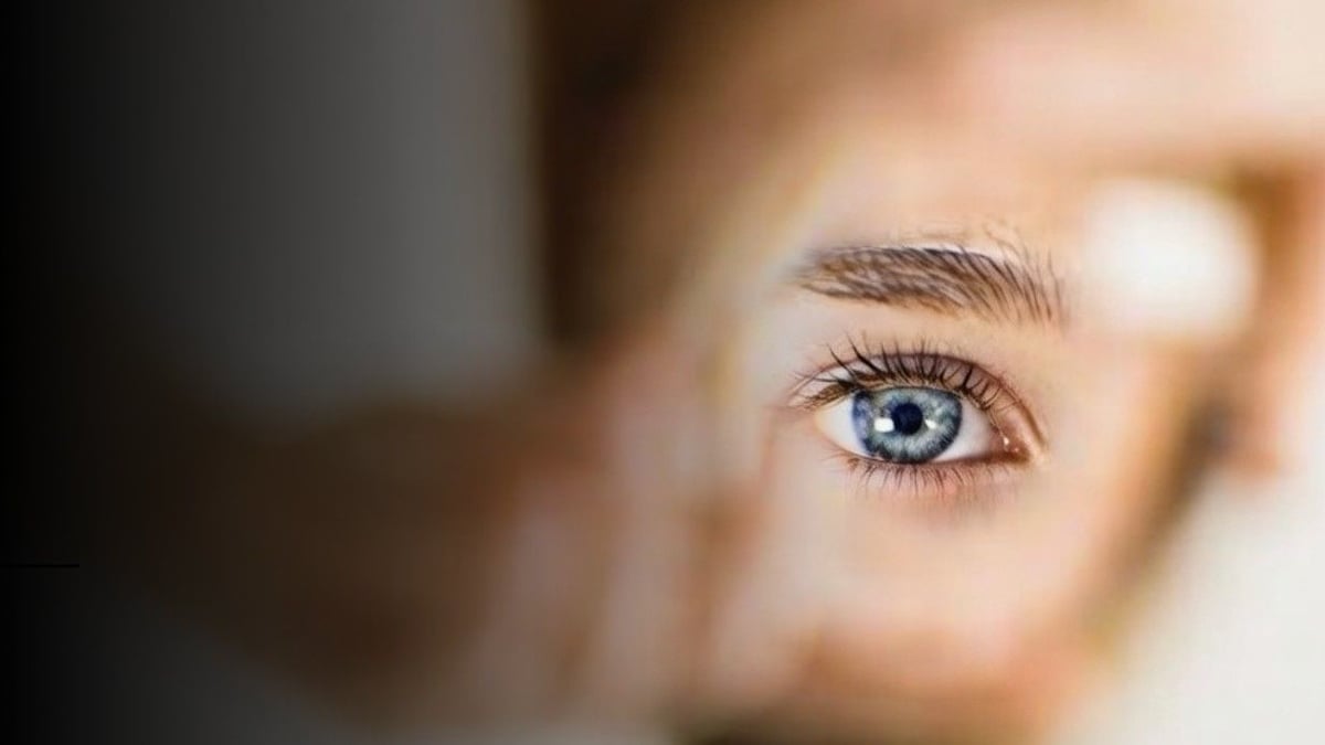 Eye of a woman peeking through a hole